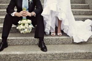 Photo of bride and groom sitting on steps, holding bridal bouquet