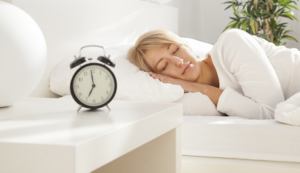 Photo of woman sleeping in bed with alarm clock on nightstand